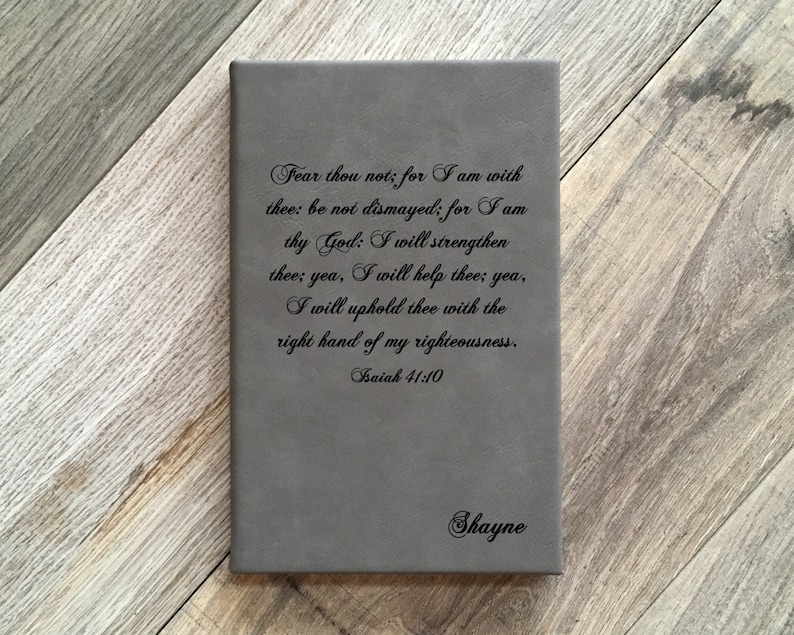 May include: A gray leather journal with the text "Fear thou not; for I am with thee: be not dismayed; for I am thy God: I will strengthen thee; yea, I will help thee; yea, I will uphold thee with the right hand of my righteousness. Isaiah 41:10" and the name "Shayne" printed on the front.