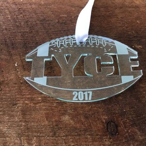 Pu&ograve; includere: Un ornamento di vetro trasparente a forma di pallone da calcio con il nome "TYCE" e l'anno "2017" incisi su di esso.