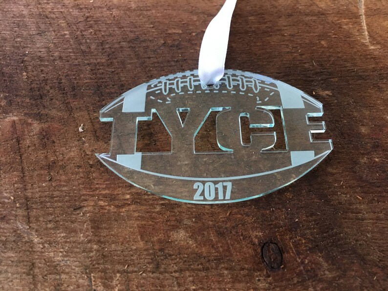 Pu&ograve; includere: Un ornamento di vetro trasparente a forma di pallone da calcio con il nome "TYCE" e l'anno "2017" incisi su di esso.
