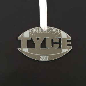 Pu&ograve; includere: Un ornamento a forma di pallone da calcio grigio e bianco con il nome "TYCE" tagliato e l'anno "2017" sotto.