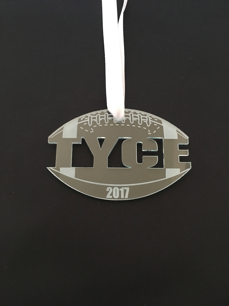 Pu&ograve; includere: Un ornamento a forma di pallone da calcio grigio e bianco con il nome "TYCE" tagliato e l'anno "2017" sotto.