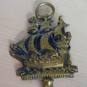 Könnte beinhalten: Ein Türstopper aus Messing in Form eines elisabethanischen Galeonen-Schiffs. Das Schiff ist mit aufwendigen Details verziert und auf einem Sockel montiert, auf dem die Worte "Elizabethan Galleon" eingraviert sind.