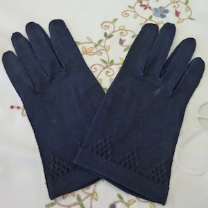 Könnte beinhalten: Ein Paar schwarze Handschuhe mit einem dekorativen Stichdetail am Handgelenk.