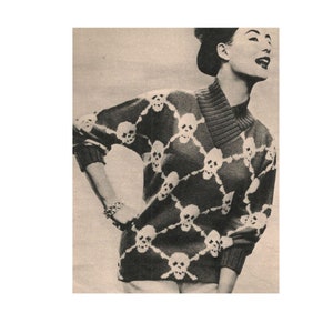 May include: A black and white knit sweater with a skull pattern. The sweater has a high collar and long sleeves.