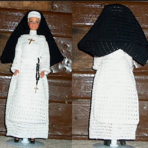 Puede incluir: Un hábito de monja blanco de ganchillo con una capucha negra de ganchillo. El hábito tiene una falda larga y fluida y un corpiño ajustado. La capucha es de forma cuadrada simple.