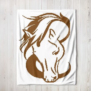 May include: A white throw blanket featuring a large, brown, pixelated graphic of a horse head in profile. The design uses a blocky, digital art style to outline the mane, ears, and facial features of the horse against the solid white background.