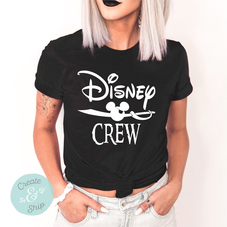 以下が含まれることがあります： 白い文字で「Disney Crew」と書かれた黒いTシャツ。Crewの文字の上にミッキーマウスの頭部のアイコンがあります。
