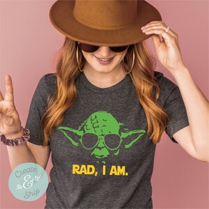May include: A dark gray t-shirt with a green Yoda character wearing sunglasses and the text "RAD, I AM." in yellow.
