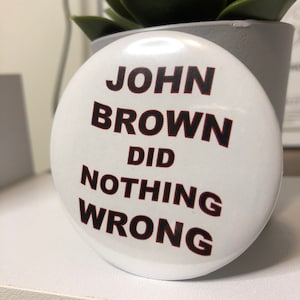 Op de afbeelding: Witte knop met zwarte tekst die "John Brown Did Nothing Wrong" luidt.