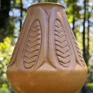 May include: A brown ceramic vase with a textured, leaf-like design. The vase has a rounded, bulbous shape and a wide opening.