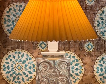 May include: A vintage table lamp with a pleated, yellow lampshade and a clear glass base with a textured, circular pattern.