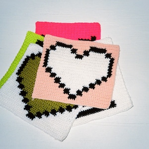 May include: Four crocheted squares with different colored backgrounds and black outlines. The top square is pink, the second is white with a black heart, the third is peach, and the bottom is green.