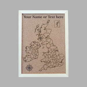 May include: A framed corkboard displaying a detailed map of the British Isles, with each county outlined. The text "Your Name or Text here" is at the top. A compass rose and a small illustration are also included. The frame is white.