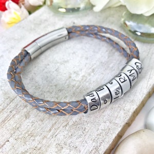 May include: A grey leather bracelet with a silver clasp and silver beads that say "Dad", "E", "I", "Love", "You", "My", and a heart.
