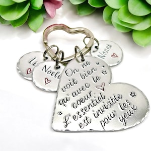 Peut inclure: Un porte-clés en forme de cœur argenté avec l'inscription "On ne voit bien qu'avec le cœur. L'essentiel est invisible pour les yeux" et trois petits breloques argentés avec les mots "Li", "Noel" et "Nanni".