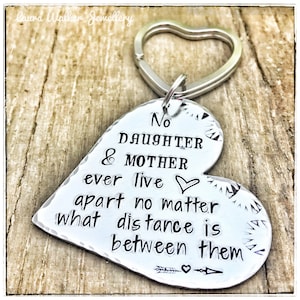 Puede incluir: Llavero de corazón plateado con el texto "No daughter & mother ever live apart no matter what distance is between them" y una pequeña flecha con un corazón en la parte inferior.