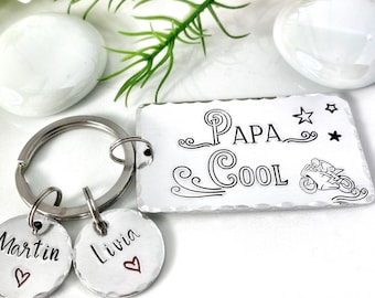 May include: Silver keyring with a rectangular tag that reads "Papa Cool" with a motorcycle graphic and two smaller tags that read "Martin" and "Livia" with hearts.