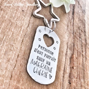May include: Silver keychain with a heart-shaped cutout and the text "Personne n'est parfait sauf ma marraine ch&eacute;rie" (No one is perfect except my dear godmother).