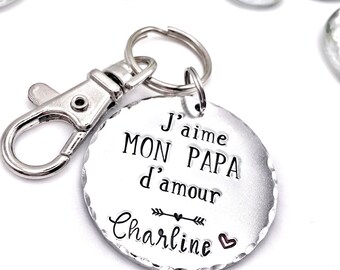 May include: Silver keyring with a round charm that says "J'aime mon papa d'amour" with an arrow and heart and the name "Charline" below.