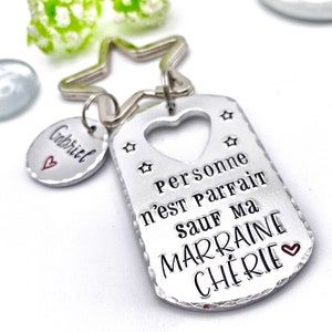 May include: Silver keychain with a star-shaped ring and a tag that says "Personne n'est parfait sauf ma marraine ch&eacute;rie" with a heart cutout and two stars. A smaller silver tag with the name "Gabriel" and a heart is attached to the ring.