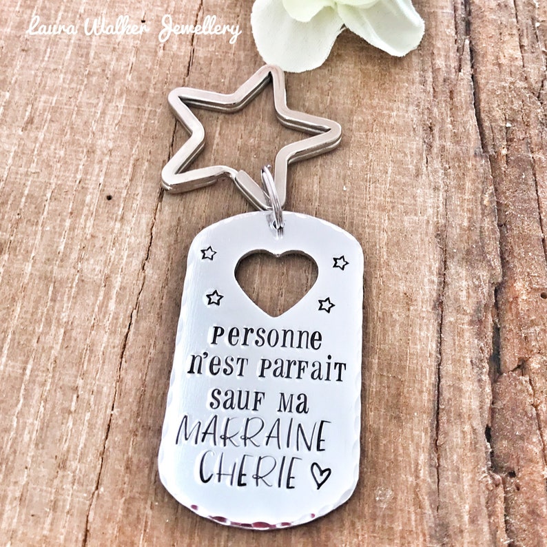 May include: Silver keychain with a star charm and a tag that says "Personne n'est parfait sauf ma marraine ch&eacute;rie" with a heart cutout.