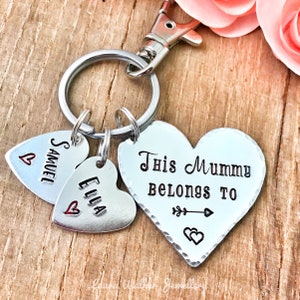 May include: Silver heart-shaped keychain with the text "This Mummy Belongs To" and two smaller heart charms with the names "Samuel" and "Ella" engraved on them.