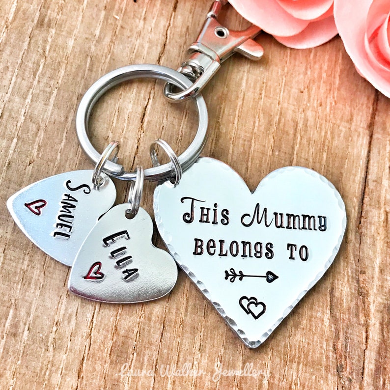 May include: Silver heart-shaped keychain with the text "This Mummy Belongs To" and two smaller heart charms with the names "Samuel" and "Ella" engraved on them.