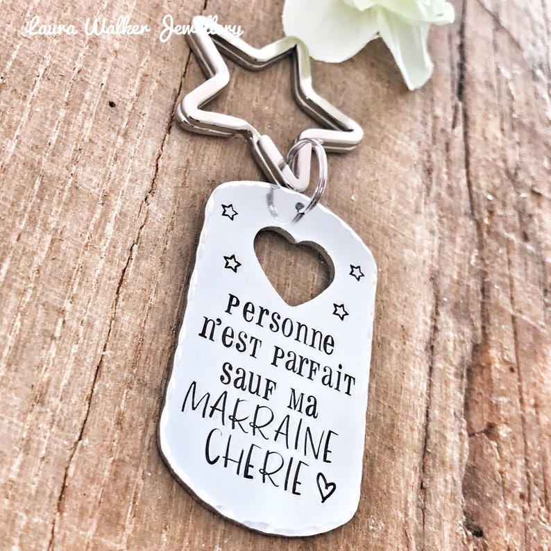 May include: Silver keychain with a star charm and a tag that says "Personne n'est parfait sauf ma marraine ch&eacute;rie" with a heart cutout.