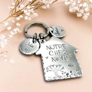 Peut inclure: Porte-clés en forme de maison argenté avec le texte "NOTRE CHEZ NOUS" et deux petites étiquettes avec les noms "Julie" et "Justin".