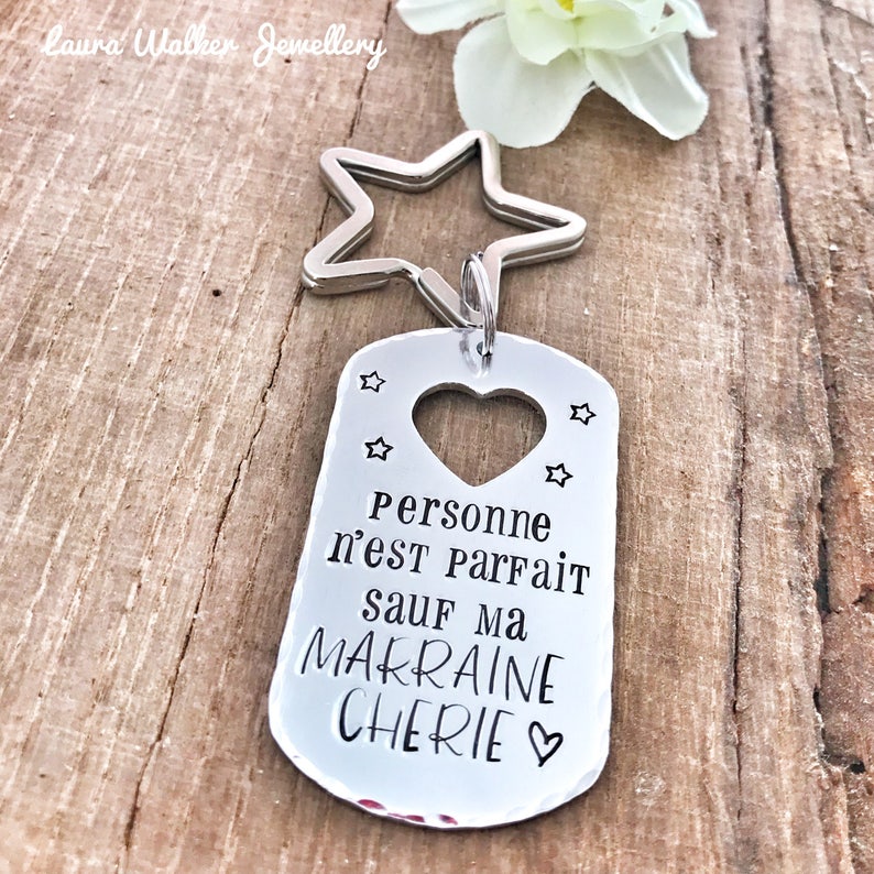 May include: Silver keychain with a star charm and a tag that reads "Personne n'est parfait sauf ma marraine ch&eacute;rie" with a heart cutout.