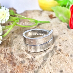 Peut inclure: Une bague en argent martelé avec une bande qui s'enroule deux fois. La bague est gravée des initiales "H & N".
