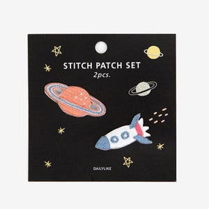 May include: A set of two embroidered iron-on patches featuring a rocket and a planet with rings. The patches are on a black background with white stars and the text "STITCH PATCH SET 2pcs. DAILYLIKE 03 Universe".