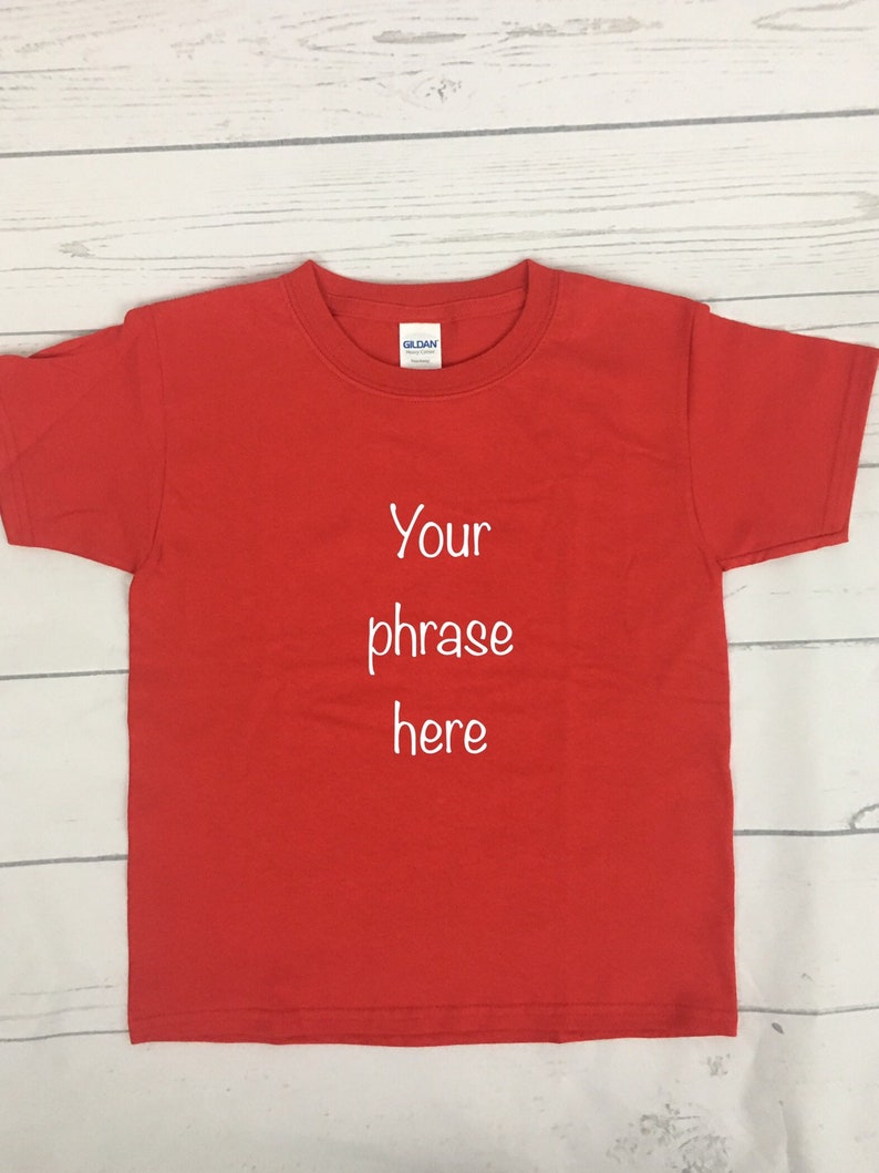 May include: Red short-sleeved t-shirt with white text that says "Your phrase here".