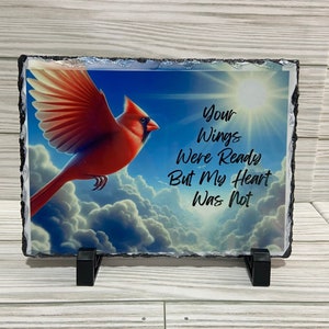 May include: A slate plaque with a red cardinal flying against a blue sky with white clouds. The plaque has the text "Your Wings Were Ready But My Heart Was Not" printed on it.