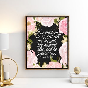 May include: A black and white printable art print with pink floral accents. The print features a quote from Proverbs 31:28: "Her children rise up and call her blessed, her husband also, and he praises her."