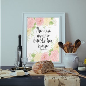 May include: A framed print with a watercolor floral design and the quote "The wise woman builds her house" with the scripture reference "Proverbs 14:1".