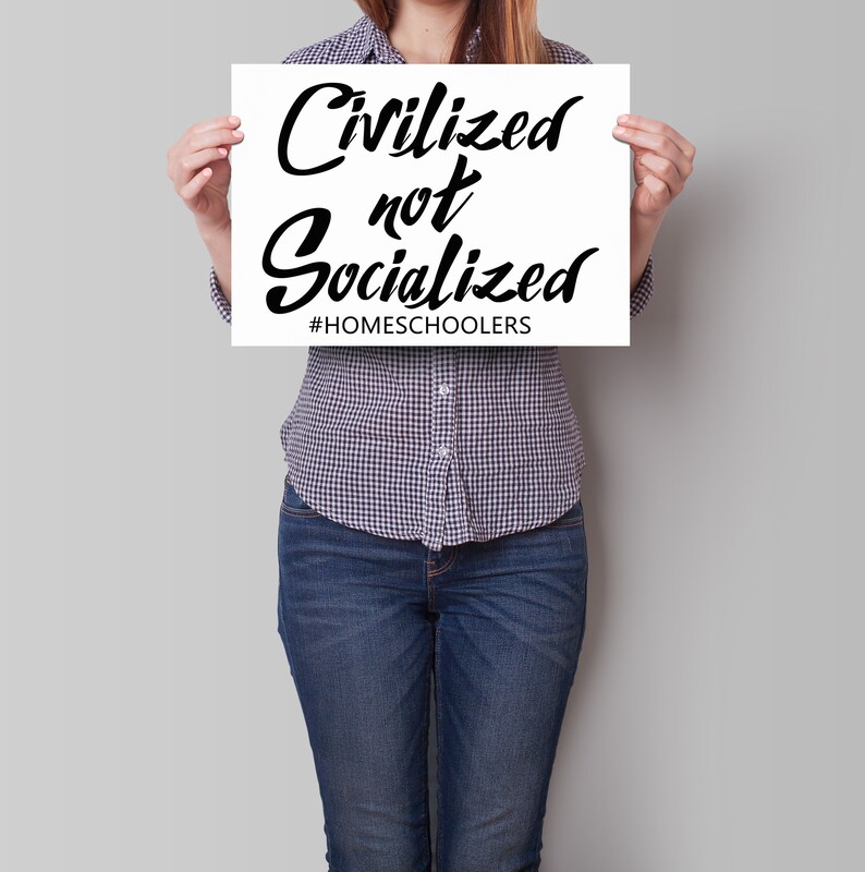 May include: A person holding a white sign with black text that reads "Civilized not Socialized #HOMESCHOOLERS".