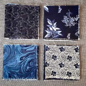 May include: Four fabric swatches with different patterns. The first swatch is black with a white floral pattern. The second swatch is black with a white leaf pattern. The third swatch is blue with a marbled pattern. The fourth swatch is white with a black floral pattern.