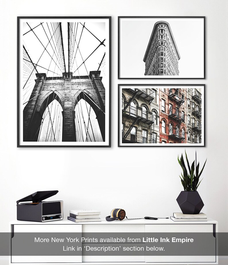 May include: Three black and white framed photographs of New York City. The first photo shows the Brooklyn Bridge from below, the second photo shows the Flatiron Building, and the third photo shows a row of brick buildings with fire escapes.