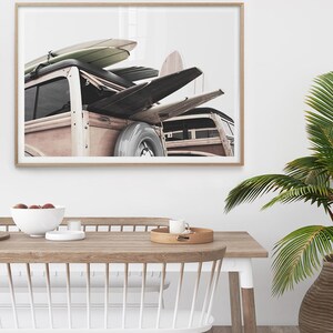 May include: A framed print featuring a vintage wood-paneled station wagon loaded with surfboards. The surfboards are in various colors and designs. The image is set against a white background, evoking a coastal, beachy theme.