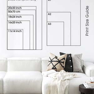 May include: A white wall with a black and white print size guide. The guide shows different sizes in inches and centimeters. The sizes are labeled A1, A2, and A3. The guide is next to a white couch with a throw blanket and pillows.
