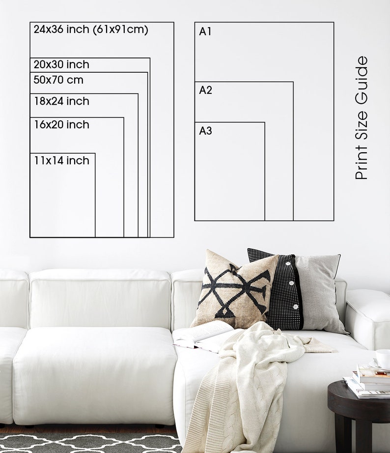 May include: A white wall with a black and white print size guide. The guide shows different sizes in inches and centimeters. The sizes are labeled A1, A2, and A3. The guide is next to a white couch with a throw blanket and pillows.