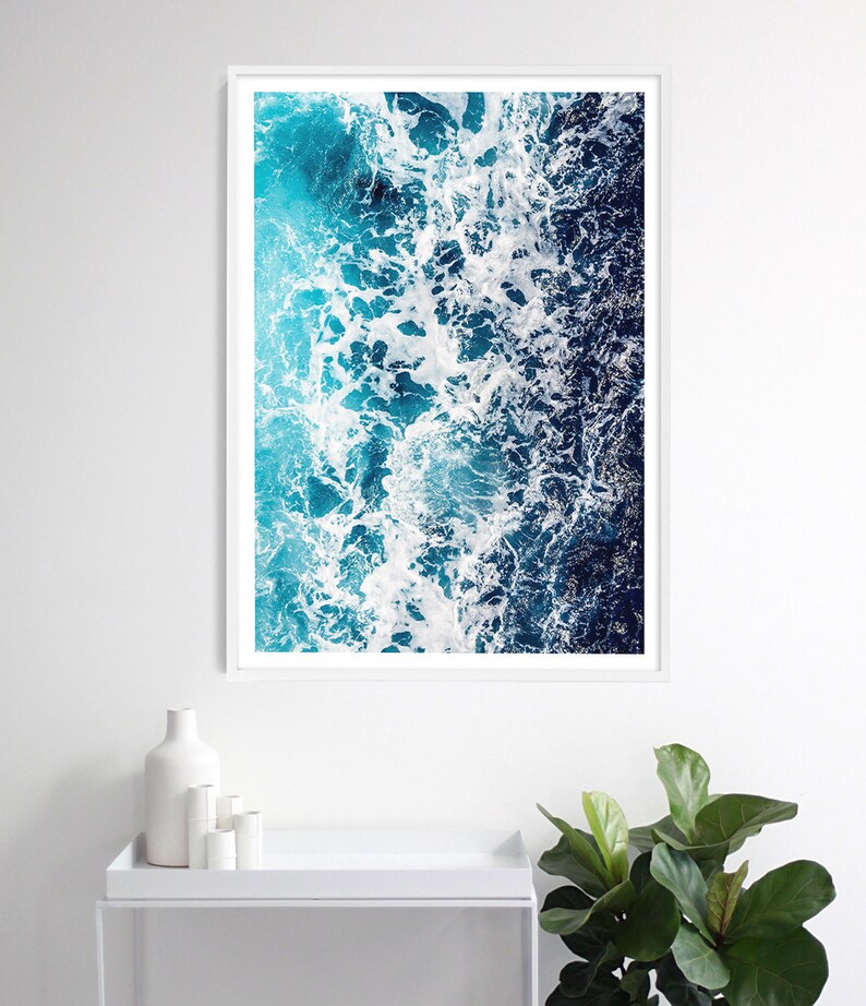 May include: A vertical rectangular wall art print featuring an aerial view of ocean waves crashing against the shore. The image displays a gradient of deep navy blue to bright turquoise water with white sea foam patterns across the surface.
