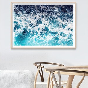 May include: A close-up photograph of ocean waves crashing, creating a foamy, white pattern against a deep blue background.