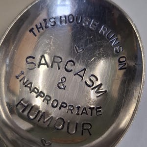 May include: A silver spoon with the text "This house runs on sarcasm & inappropriate humour" engraved on it.