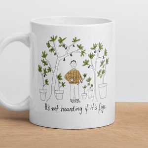 Puede incluir: Taza de cerámica blanca con un dibujo en línea negra de una persona de pie frente a cinco higueras en maceta. El texto "It's not hoarding if it's figs." está impreso en la taza.