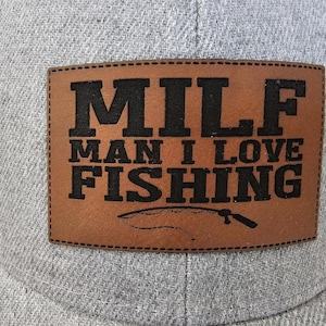 May include: A gray and brown baseball cap with a brown leather patch that says "MILF MAN I LOVE FISHING" in black letters. The patch also has a fishing rod and hook design.