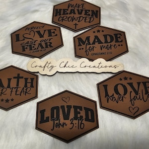 May include: A collection of brown, hexagon-shaped wooden signs with black lettering. The signs feature inspirational quotes like "Perfect Love Cast Out Fear" and "Made for More." A wooden sign with the text "Crafty Chic Creations" is also present.