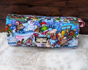 May include: A colorful Christmas-themed clutch bag with a variety of cartoon characters, including a snowman, a penguin, and a reindeer. The bag has a gold metal clasp and a red and white striped strap.