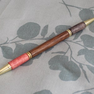 Un stylo à bille bicolore pour étudiant ou enseignant avec un corps tourné à la main en noyer noir, avec des garnitures en or poli.